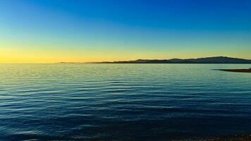 sunset on the Ocean Calmness calm sea on Vancouver Island resting in trailers on the shore bright colors of dark blue orange stripe on the horizon from the sun rich space for text travel advertising photo