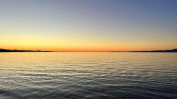 sunset on the Ocean Calmness calm sea on Vancouver Island resting in trailers on the shore bright colors of dark blue orange stripe on the horizon from the sun rich space for text travel advertising photo