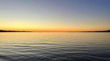 sunset on the Ocean Calmness calm sea on Vancouver Island resting in trailers on the shore bright colors of dark blue orange stripe on the horizon from the sun rich space for text travel advertising photo