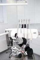 dental office for children Zebra toy soft toy with real teeth sits near tools in dentistry in a dental chair space for text white background frequency tidiness sterility photo