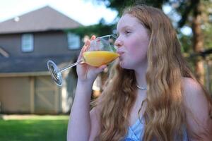 niña bebidas naranja jugo en el calles pasión Fruta limonada. verano beber. para llevar limonada. frío limonada con hielo en un hembra mano en contra un río vista. bailando con un bebida en mano foto