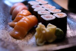 Sushi conjunto sabroso y apetitoso Sushi. Sushi con rebanadas de salmón y Fresco pepinos rojo jengibre y verde wasabi en un de madera tablero fueron servido a Sushi. Sushi rojo continuar foto