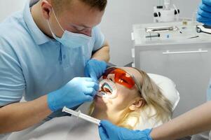 Dentist making whitening to patient in stomatology liquid cofferdam to isolate the gums from the action of a bleaching agent optragat rotary spreader photo
