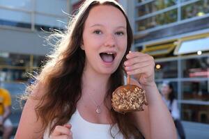 A girl eats a chocolate-covered apple on Greenville Island promenade photo