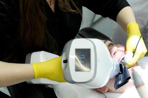 niña en un radiografía habitación hace un panorámico imagen de su dientes. rengen equipo en el clínica. salud cuidado concepto paciente retrato en un dental clínica foto