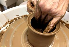 Women's hands making a kitchen object from clay on a potter's wheel manual potter wheel is rotated on a vertical axis with one hand and the product is formed with the other hand photo