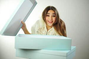 Birthday gift A young woman in a white blouse with fur on a white background near the box received a delivery Studio shooting on a white background blue boxes girl is happy and joyful photo