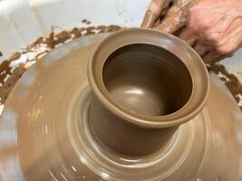 Women's hands making a kitchen object from clay on a potter's wheel manual potter wheel is rotated on a vertical axis with one hand and the product is formed with the other hand photo