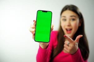 Hey look.green screen chromakey phone Smiling pretty female model pointing fingers left inviting to check it out, showing advertisement on white background woman showing hand for product advertising photo