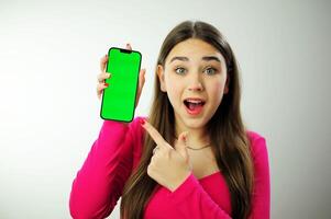 girl phone chromakey delight a woman in a pink sweater with multi-colored manicure long hair is happy showing her phone she has blue eyes she is happy advertising was looking for what she found photo