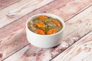 chinese mixed vegetables with capsicum, tomato, carrot, and radish served in bowl isolated on wooden table background closeup side view of bangladeshi food photo