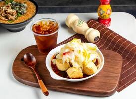 apestoso tofu con bebida y cuchara servido en maceta aislado en de madera tablero de cerca lado ver de Taiwán comida foto