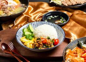 Pork Rice with tomato, cucumber, fork and spoon served in dish isolated on wooden board side view of asian food photo