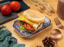 Ham and egg muffin burger with cherry tomato, spoon and fork served in dish isolated on wooden table side view of taiwan food photo