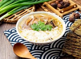 Ancient style mushroom and meat rice soup with spring onion, spoon and chopsticks served in bowl isolated on napkin side view on table taiwan food photo