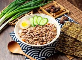 Roast duck rice with egg, cucumber, spring onion, spoon and chopsticks served in bowl isolated on napkin side view on table taiwan food photo