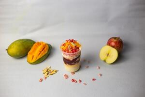 Faluda with fruits, apple, mango and pomegranate seeds served on glass isolated on grey background side view of indian, bangladeshi and pakistani dessert photo