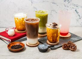 Assorted Taiwan iced tea Oolong milk Latte, Green tea latte, Strawberry Lemon tea, ice Oreo milk tea, served in disposable glass isolated on board side view of taiwanese iced drink photo