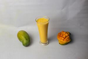 Mango milkshake with straw served in glass isolated on grey background side view of healthy drink photo