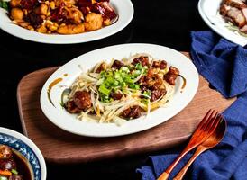 Salt and pepper intestines with spring onion, spoon and fork served in dish isolated on wooden board side view of taiwan food photo