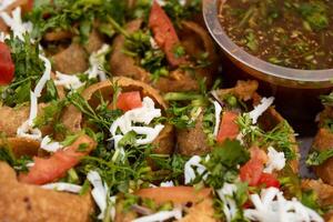 Fuchka, pan puri, or gol gappa filled with herbs with spicy water served in plate isolated on wooden table closeup side view of bangladeshi street food photo