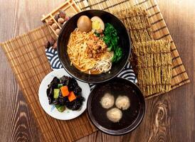 sesame paste noodles with Black Fungus, meatballs soup, minced pork meat, preserved egg and chopsticks served in plate isolated on napkin top view on table taiwan food photo