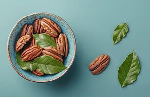 Bowl Filled With Nuts and Leaves on Blue Surface photo