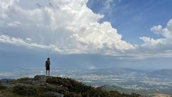 un hombre soportes en el más alto montaña en Portugal él mira dentro el distancia él ve En todas partes el cielo montañas y espacio un lote de espacio para texto para viaje publicidad foto