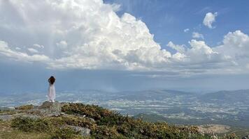 en el más alto montaña en Portugal soportes un niña su pelo golpes en el viento en pie en parte superior de el montaña relajante y disfrutando hermosa verano montaña paisaje. un panorámico ver foto