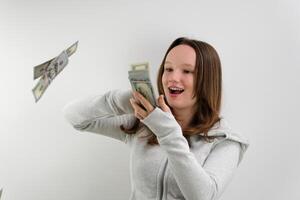 satisfied happy teenage girl scatters 100 dollar bills in different directions slow motion on a white background sports jacket rich man throwing money away not thinking about the future photo