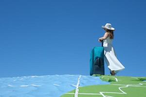 young girl in white dress and huge hat with a suitcase travels around globe Close up woman legs walks on asphalt road and traveling world with travel suitcase . Female hitchhiking around country photo