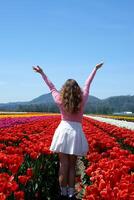 collection of videos and photos where a girl in a white skirt walks through field with tulips blue background sky mountains bright flowering fields teenager young woman walk outdoors beauty self-care