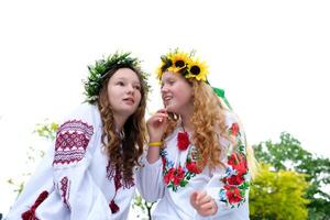 Midsummer. Two girls in the Slavic clothes weave braids in the hair near the fire. photo