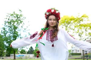 beautiful Ukrainian young woman tender girl in a large red wreath of bright pink white red flowers braiding ribbons in hair wind tenderness cleanliness peace in Ukraine Peacetime people Real life photo