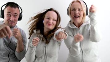 cheerful sports family boxing with fists at the camera in headphones listening to music dancing man girl woman making faces laughing outstretched fists defending white background photo