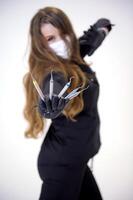 Beautiful woman dentist in a black suit with a white mask with flowing hair holds in her hands scaler and curette Hand stretched forward selective focus bright photo of gorgeous woman