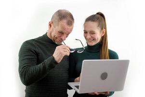 sincere laughter bewildered man through glasses looks at screen of laptop monitor Is it really so serious balding beard mustache Gray hair Green jacket white background joy winning joke embarrassment photo