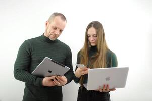 Helpful male boss mentor coach teacher explaining new online project to young female worker student intern, focused leader executive manager training instructing trainee pointing iphone macbook ipad photo