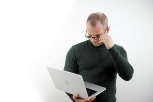 through eyes of buyer professor is preparing for Macbook 14 Pro lecture technical characteristics of laptop new generation of technology balding middle-aged man in glasses is reading text on laptop photo