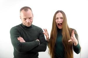 Conflict, quarrel, jealousy in the family home. Young couple, man and woman. The woman is jealous, takes the phone from her husband, demands an explanation photo