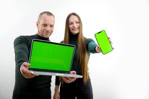 man and woman in hands with laptop and phone green screen chroma key space for text on white background cheerful happy faces good choice sale advertising product offer to extend arms forward photo