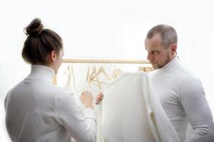 Tailor standing near male client measuring back. Tailor woman taking measures for new business shirt using tape meter. Young fashion designer taking measurement of man wearing shirt in store. photo