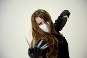 Beautiful woman dentist in a black suit with a white mask with flowing hair holds in her hands scaler and curette Hand stretched forward selective focus bright photo of gorgeous woman