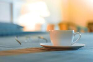 un taza de café y lentes en un cabecera mesa foto