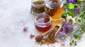 Raw organic bee pollen and honey in jars and wild flowers. video