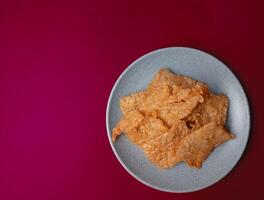 Tempe goreng. Delicious fried tempeh from Indonesia Asian culinary isolated on red background photo