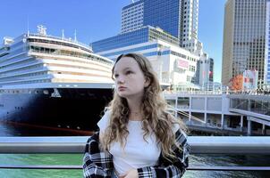 The cruise liner sailed to the coast of Canada, the girl went out for a walk to see the sights Traveling across the ocean on a huge ship Go round the world Dreamy look of experiencing anxiety joy photo