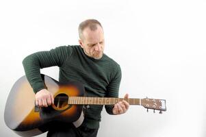 a man tunes a guitar male hands and a guitar close-up of a musician playing an acoustic guitar. Music white background advertising green sweater photo