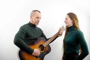 man playing guitar to woman tunes a guitar male hands and a guitar close-up of a musician playing an acoustic guitar. Music white background advertising green sweater photo