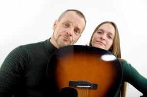 a man and a woman leaned their chins on the guitar looking into the frame photo